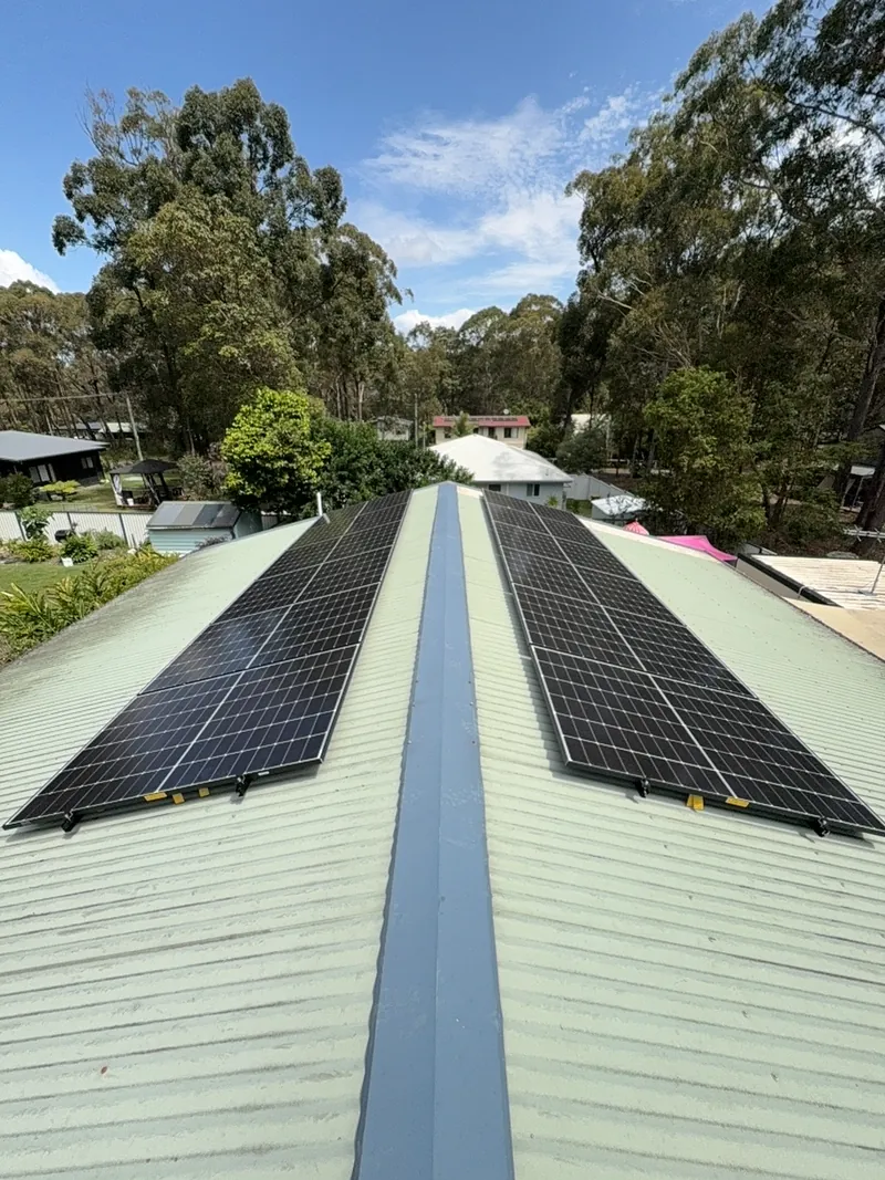 Two rows of solar panels either side of the ridge on a green Colorbond roof